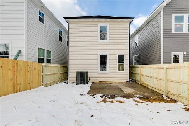 snow covered property with cooling unit and a fenced backyard