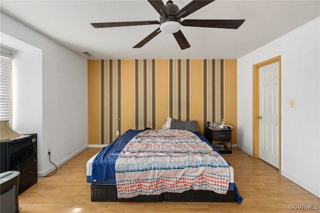 bedroom featuring light wood finished floors, visible vents, baseboards, and wallpapered walls