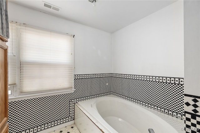 full bathroom with tile walls, visible vents, and a bath