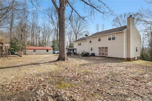 rear view of property featuring a chimney, central AC unit, and a playground