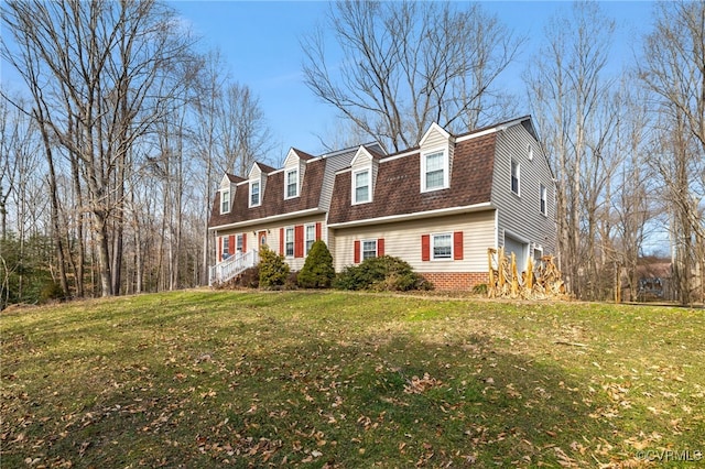 colonial inspired home with a garage, a front yard, roof with shingles, and a gambrel roof