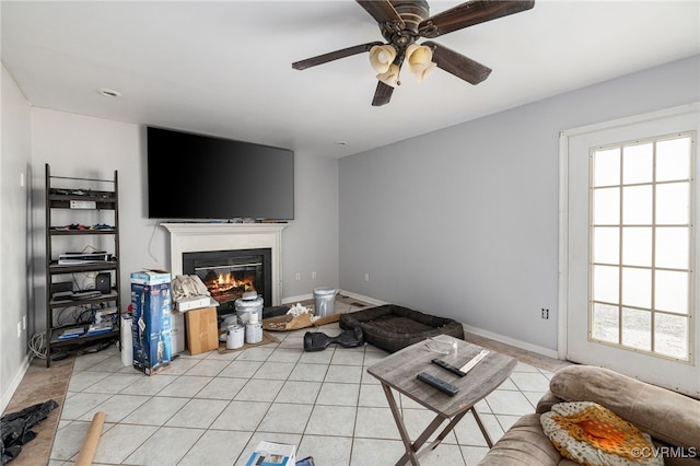 living room with a glass covered fireplace, light tile patterned flooring, and baseboards