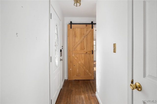 hallway with dark wood-style floors, a barn door, and baseboards