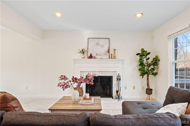 carpeted living area featuring recessed lighting, a tiled fireplace, and baseboards