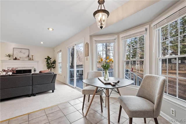 dining room with light tile patterned floors, a tile fireplace, a notable chandelier, recessed lighting, and light colored carpet