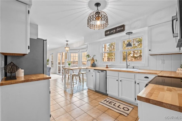 kitchen featuring hanging light fixtures, stainless steel dishwasher, white cabinetry, a sink, and wood counters