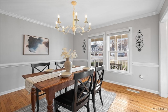 dining space with ornamental molding, wood finished floors, visible vents, and an inviting chandelier