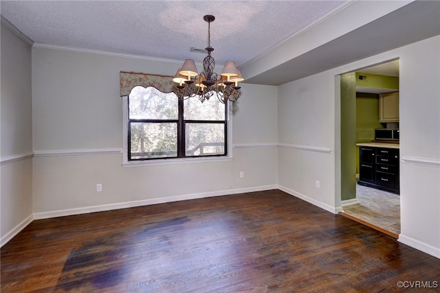 spare room featuring baseboards, ornamental molding, dark wood-type flooring, an inviting chandelier, and a textured ceiling