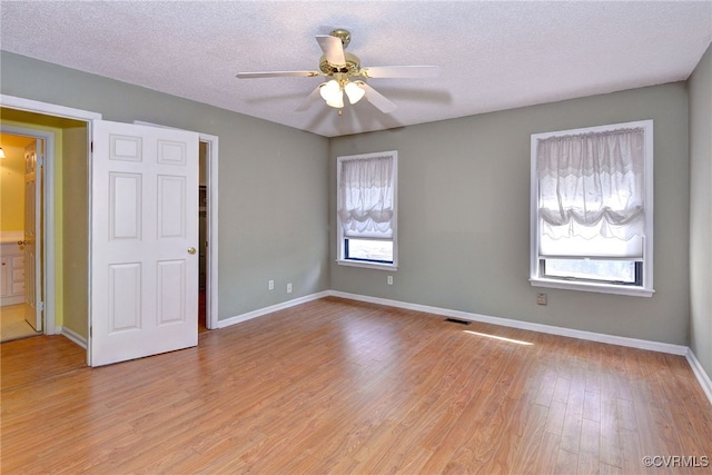 unfurnished bedroom with light wood-style floors, visible vents, a textured ceiling, and baseboards