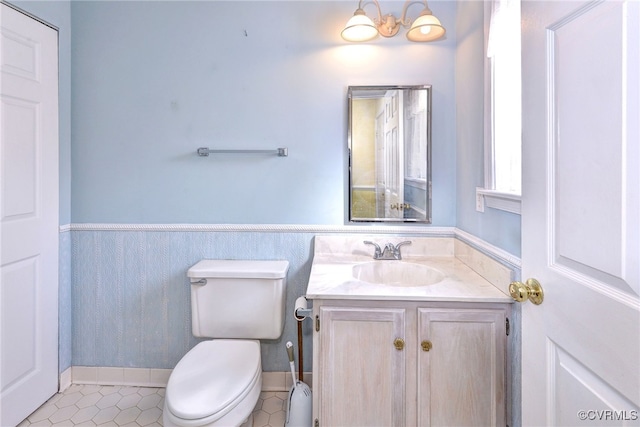 half bathroom featuring wainscoting, vanity, and toilet