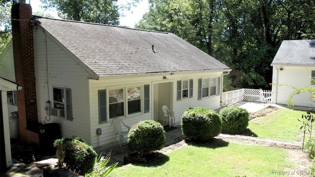 view of front facade with a shingled roof, fence, a chimney, and a front lawn