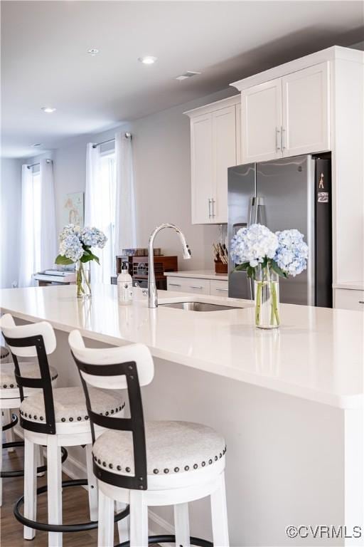 kitchen with light countertops, stainless steel refrigerator with ice dispenser, and white cabinetry