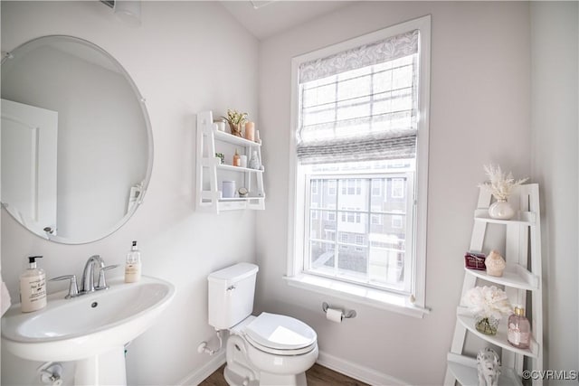 half bathroom featuring a sink, toilet, and baseboards