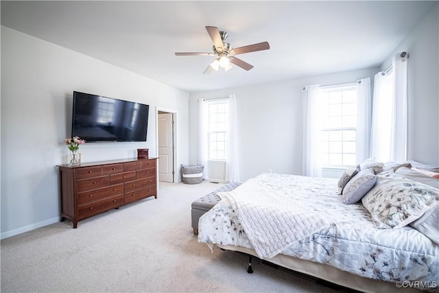 bedroom with a ceiling fan, light colored carpet, multiple windows, and baseboards