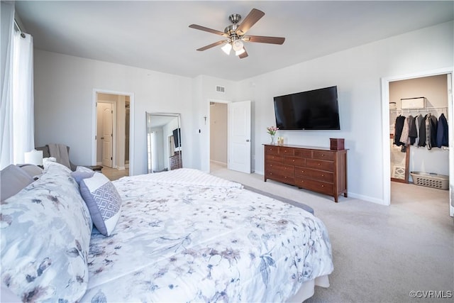 bedroom with light carpet, visible vents, a ceiling fan, baseboards, and a spacious closet