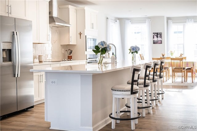 kitchen featuring a kitchen island with sink, white cabinetry, light countertops, and stainless steel fridge with ice dispenser