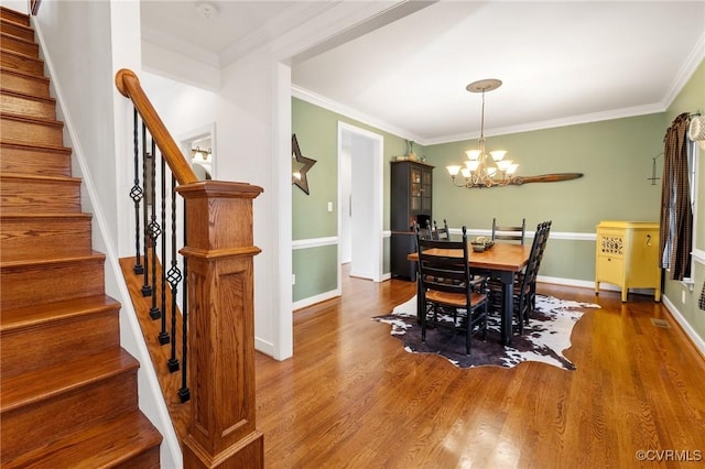 dining space featuring wood finished floors, a chandelier, and ornamental molding