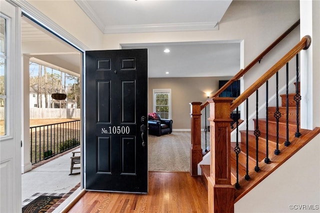 foyer featuring stairway, crown molding, baseboards, and wood finished floors