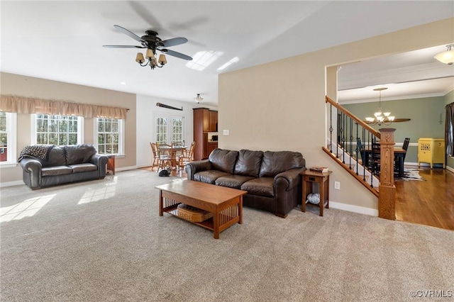 living area with stairway, baseboards, carpet, and ceiling fan with notable chandelier