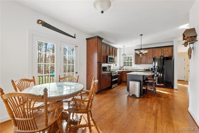 kitchen with wood finished floors, appliances with stainless steel finishes, a kitchen breakfast bar, decorative light fixtures, and a center island