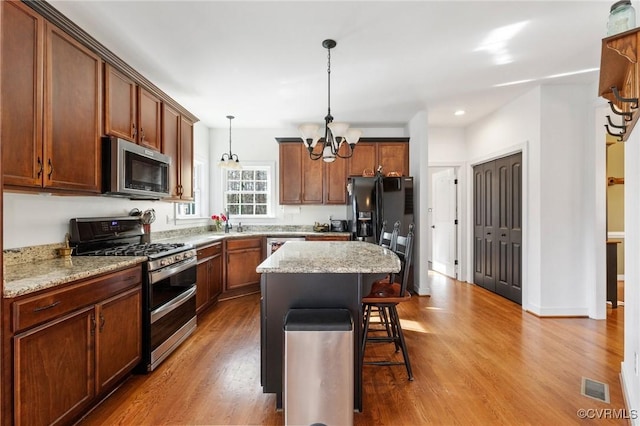 kitchen featuring visible vents, a kitchen breakfast bar, stainless steel appliances, and wood finished floors