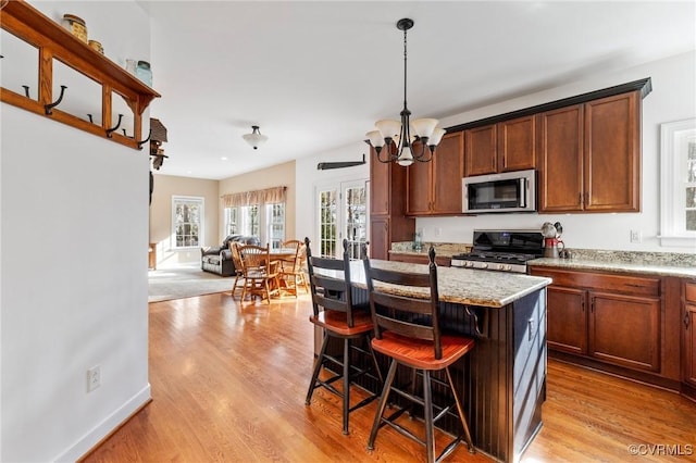 kitchen featuring a notable chandelier, appliances with stainless steel finishes, open floor plan, and light wood finished floors