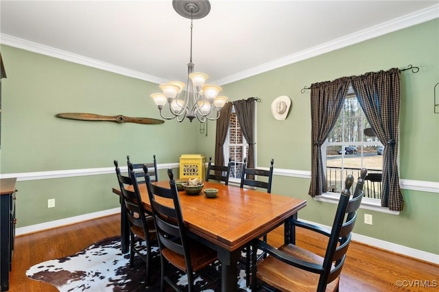 dining space featuring baseboards, an inviting chandelier, wood finished floors, and crown molding