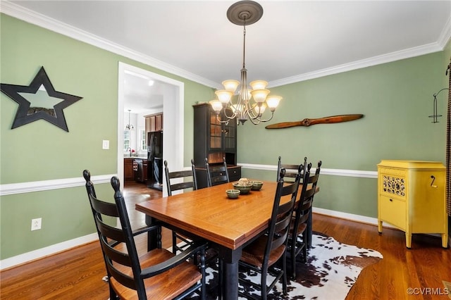 dining space with baseboards, wood finished floors, and ornamental molding