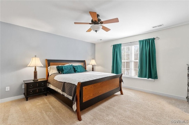 bedroom with ceiling fan, light colored carpet, visible vents, and baseboards