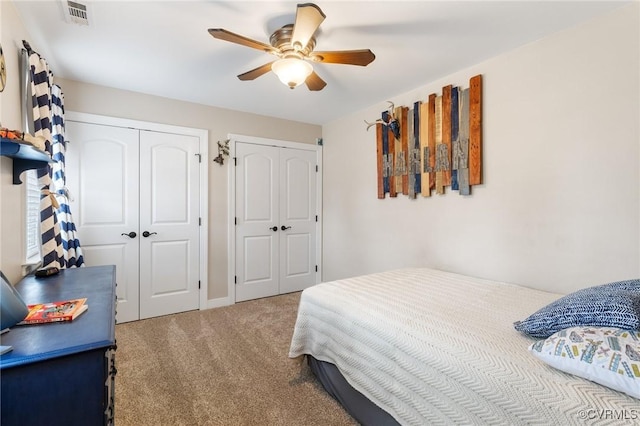 bedroom with ceiling fan, carpet, visible vents, and multiple closets