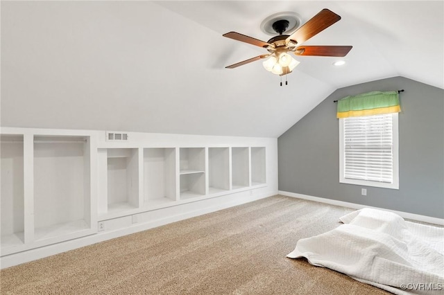 additional living space featuring visible vents, built in shelves, a ceiling fan, carpet floors, and vaulted ceiling