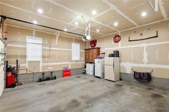 garage with a garage door opener and freestanding refrigerator