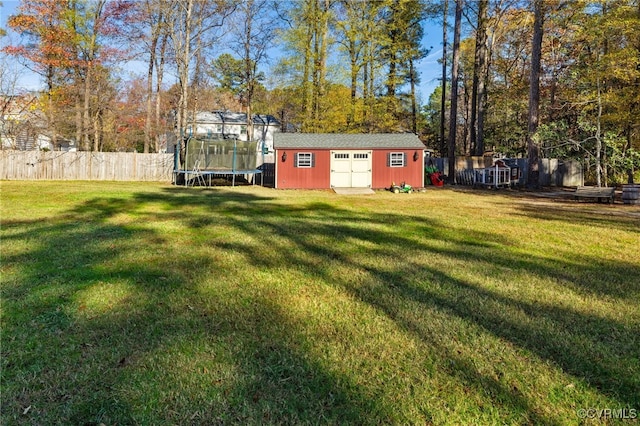 view of yard with a storage unit, an outbuilding, a trampoline, and a fenced backyard