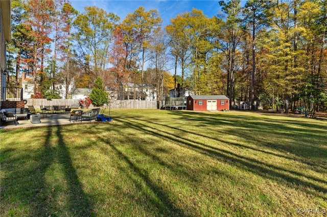 view of yard with a patio area, an outdoor structure, a trampoline, and fence