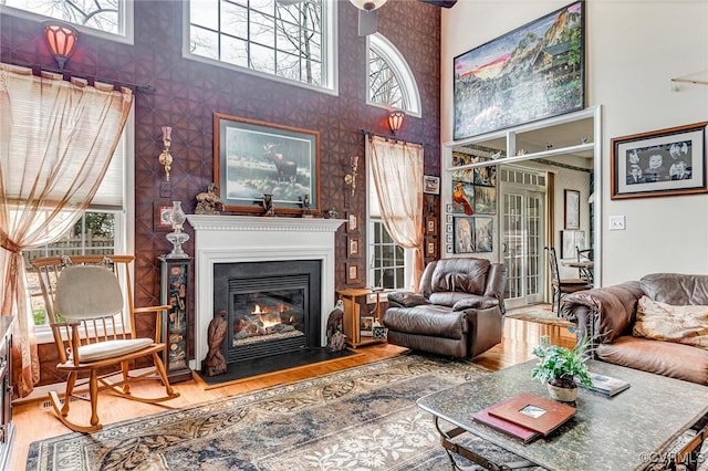 living area featuring a glass covered fireplace, a high ceiling, and wood finished floors