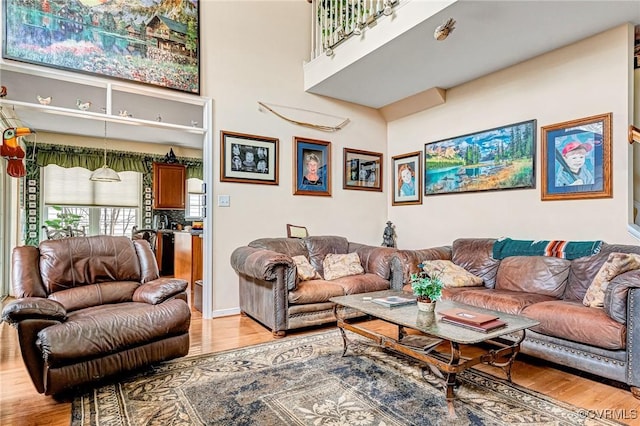 living area with a towering ceiling and light wood-style flooring