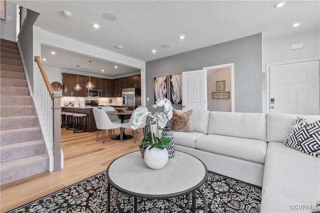 living room featuring light wood-style flooring, stairway, and recessed lighting