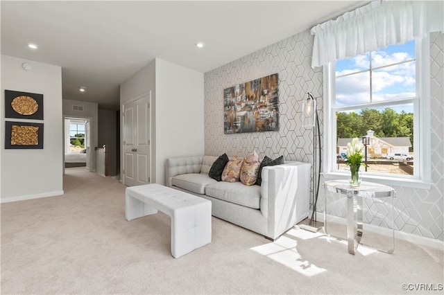 living room with an accent wall, recessed lighting, visible vents, and light colored carpet