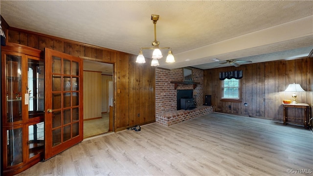 living area featuring a ceiling fan, wood walls, a textured ceiling, and wood finished floors