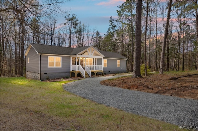 view of front facade with crawl space, driveway, covered porch, and a lawn