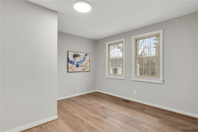 empty room with visible vents, light wood-style flooring, and baseboards