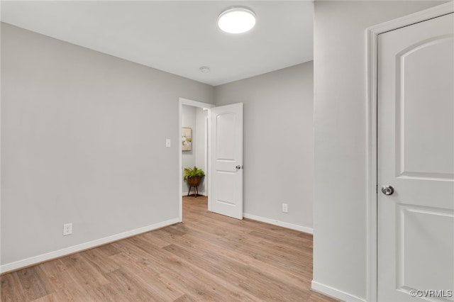 empty room featuring light wood finished floors and baseboards