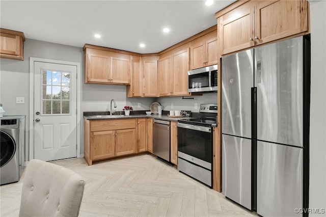 kitchen featuring recessed lighting, light brown cabinetry, appliances with stainless steel finishes, a sink, and washer / dryer