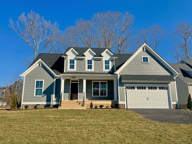 view of front facade with driveway, covered porch, an attached garage, and a front yard