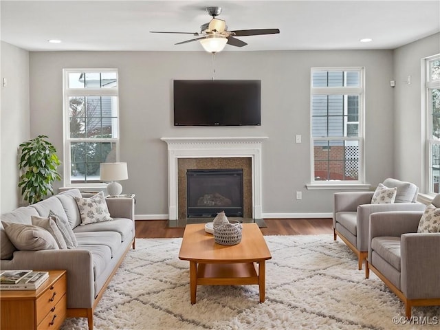 living area featuring a fireplace with flush hearth, recessed lighting, baseboards, and wood finished floors