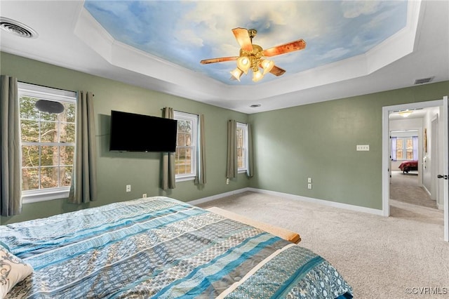 carpeted bedroom featuring visible vents, multiple windows, and a raised ceiling