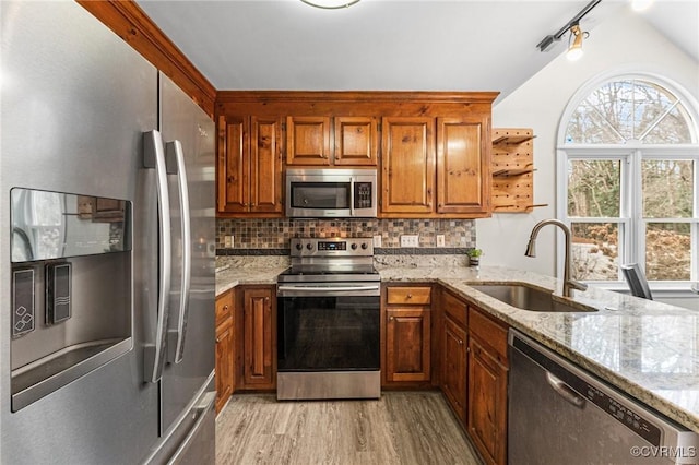 kitchen featuring a sink, stainless steel appliances, brown cabinets, and tasteful backsplash