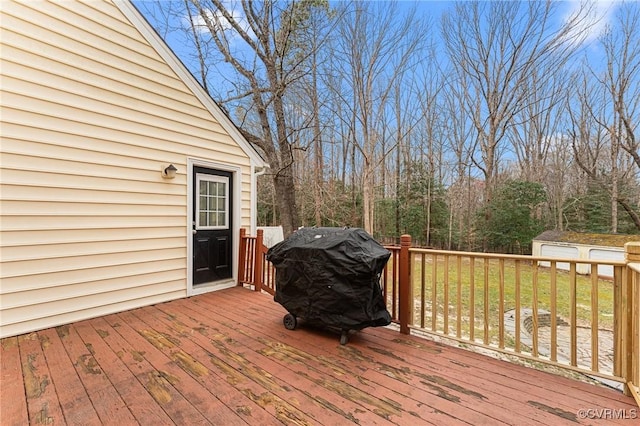 wooden terrace with grilling area, a storage shed, and an outdoor structure