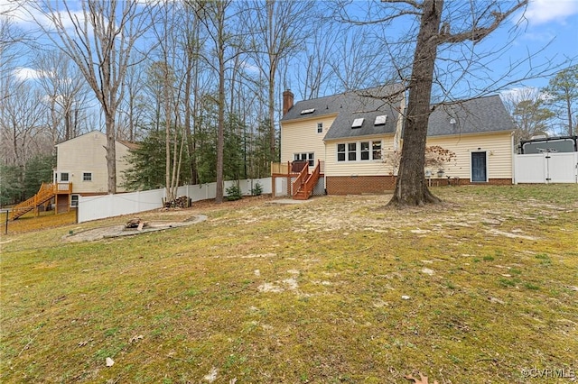 back of house with stairway, a yard, a chimney, and fence