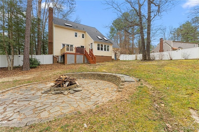 back of property featuring stairway, a yard, a fenced backyard, a fire pit, and a deck